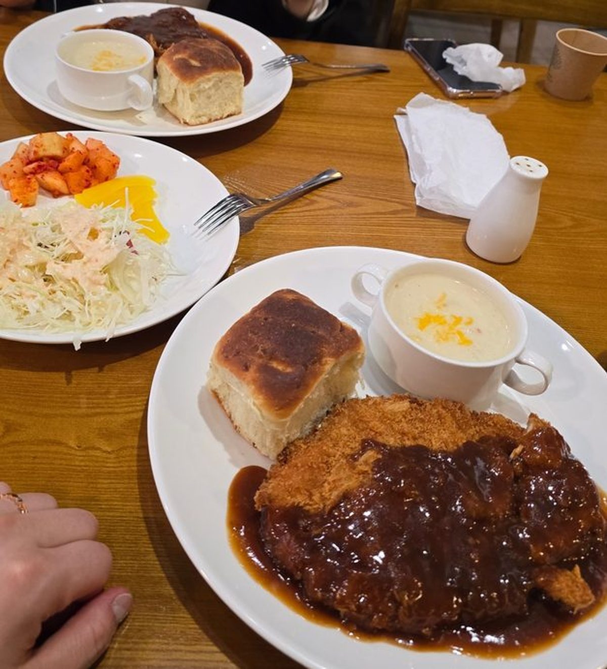 Table setup for two — both plates of donkatsu with bread and soup, plus the shared banchan plate
