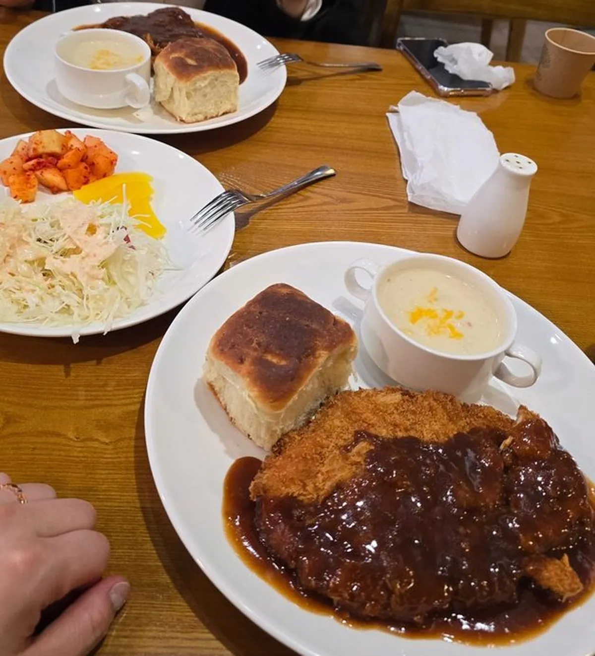 Table setup for two — both plates of donkatsu with bread and soup, plus the shared banchan plate