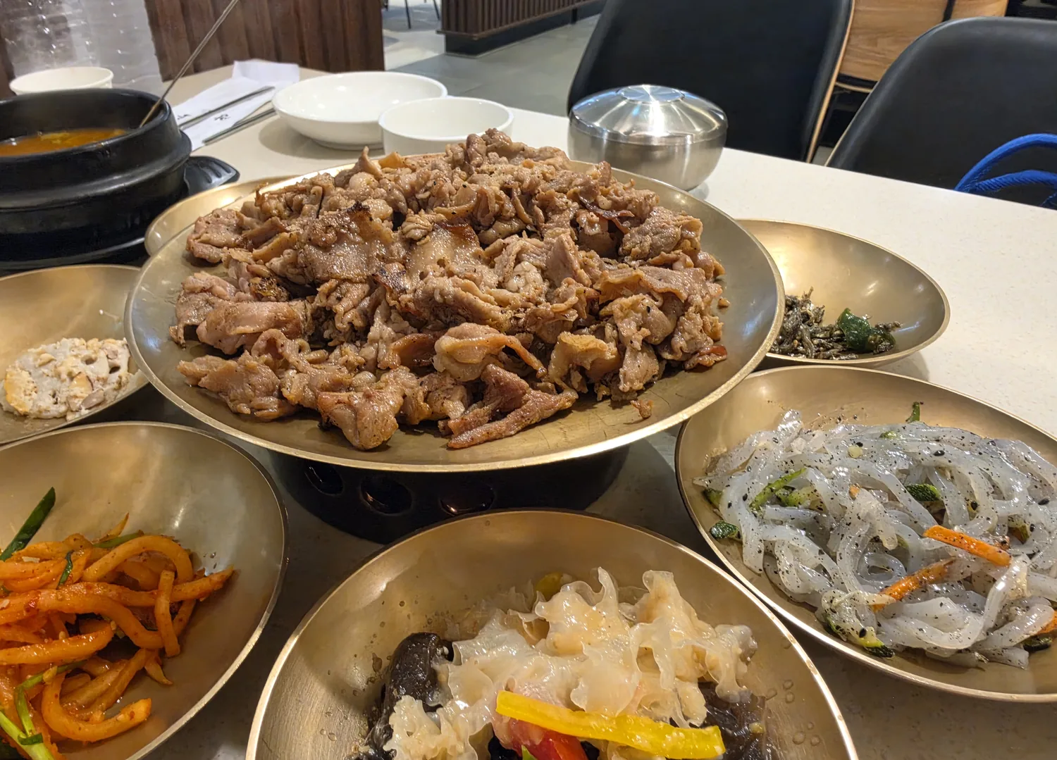 Charcoal pork bulgogi with brass bowls of banchan at Gwangneung Ok Dogok Seoul Korean BBQ