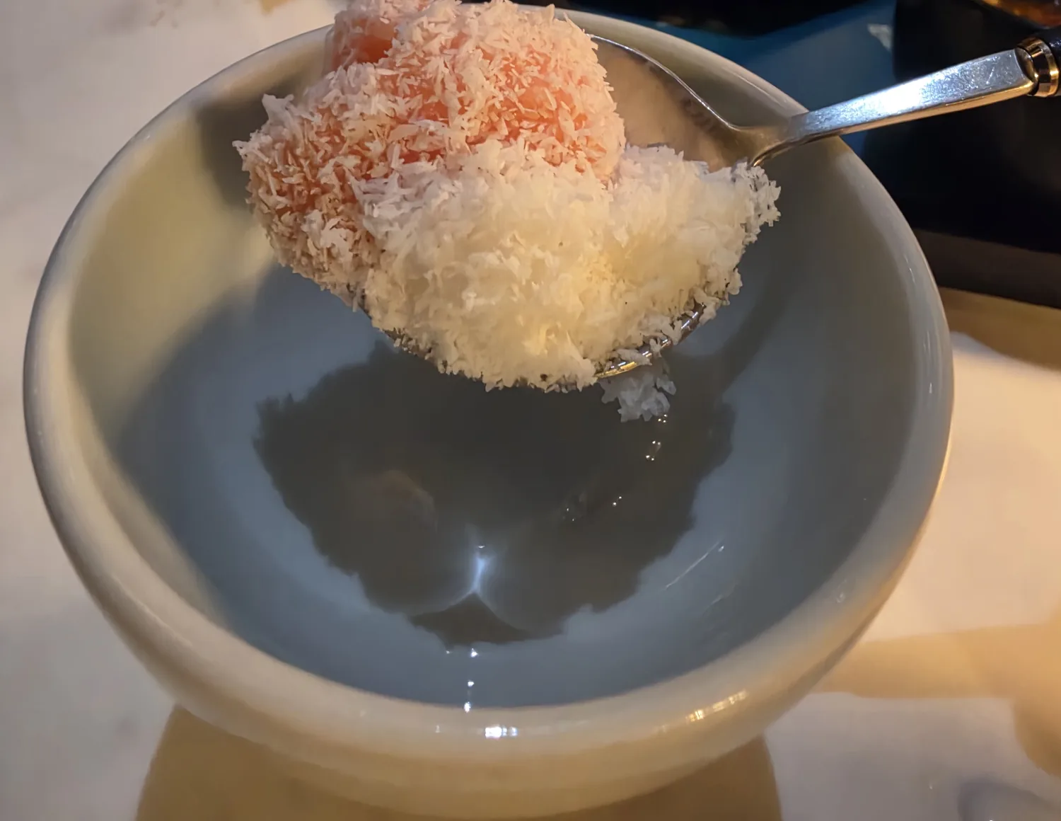 Spoonful of tomato bingsu with milk ice and coconut flakes